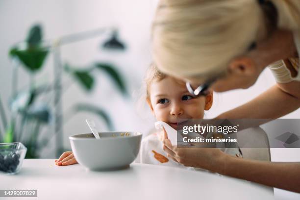 unrecognizable mother cleaning her daughter after breakfast in the morning - tissue stockfoto's en -beelden