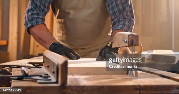 male carpenter cutting wooden plank - table saw stock pictures, royalty-free photos & images