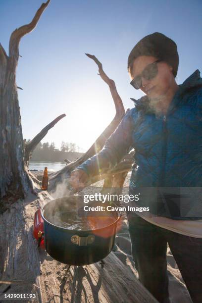 a camper stirring a pot while making dinner on the beach - sunset bay state park stockfoto's en -beelden