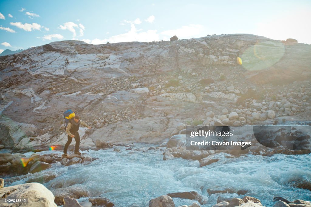 A mountaineer carefully makes his way across a rushing mountain river, Garibaldi Provincial Park