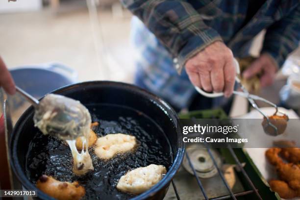 man preparing traditional oliebollen dutch doughnuts, langley, british columbia, canada - oliebol stock pictures, royalty-free photos & images