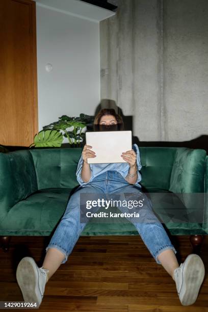 woman sitting on couch and using tablet - camera flashes stock pictures, royalty-free photos & images