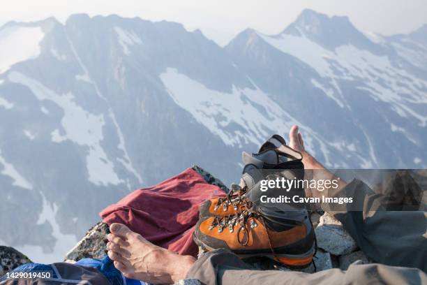 hiker resting after reaching top of ashlu mountain in coast mountain range, squamish, british columbia, canada - barefoot snow stock pictures, royalty-free photos & images