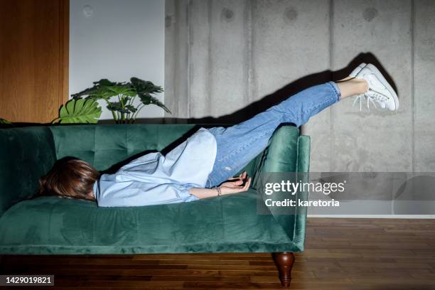 tired woman laying face down on couch - home concepts stock-fotos und bilder