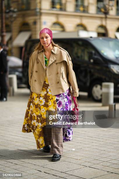 Guest wears a pink sequined / rhinestones hat, earrings, a beige oversized buttoned jacket, a purple / yellow / green flower print pattern yoke...