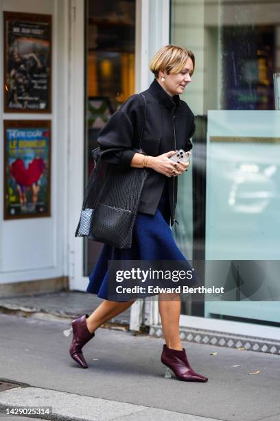 Guest wears white pearls earrings, a black zipper jacket, a black t-shirt, a navy blue felt midi skirt, a black mesh shoulder bag, gold bracelets,...