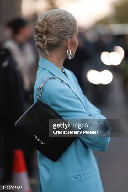 Caroline Daur is seen wearing silver Tiffany & Co. Earrings and necklace, light blue oversize blazer jacket, and a black leather Off-White shoulder...