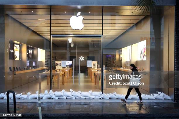 Woman walks past a shuttered Apple store in the historic district as the city prepares for Hurricane Ian to make landfall on September 30, 2022 in...