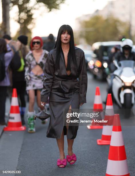 Fiona Zanetti is seen wearing a dark brown silk v-neck slit midi dress with long sleeves, a brown LV monogram print pattern Louis Vuitton clutch,...