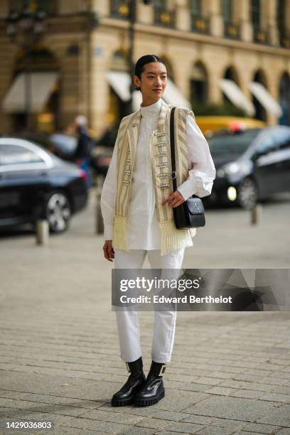 Guest wears a white high neck blouse, a pale yellow and black striped print pattern sleeveless / fringed borders / with embroidered crystal buttons...