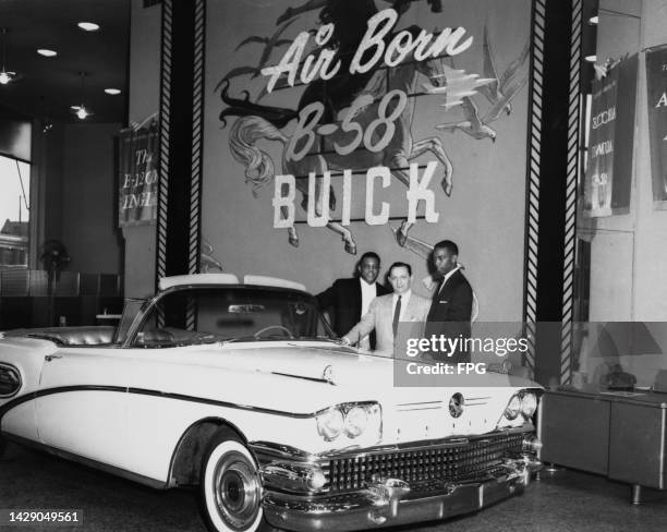 American baseball player Willie Mays, Buick sales manager Moe Wysocky, and American baseball player Ernie Banks pose with a Buick Limited convertible...