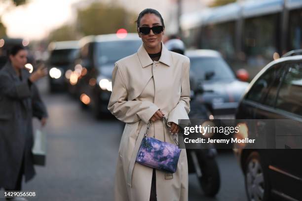 Tamara Kalinic is seen wearing black sunglasses, beige leather Off-White long trench coat, purple tie-dye shoulder bag from Off-White, outside...