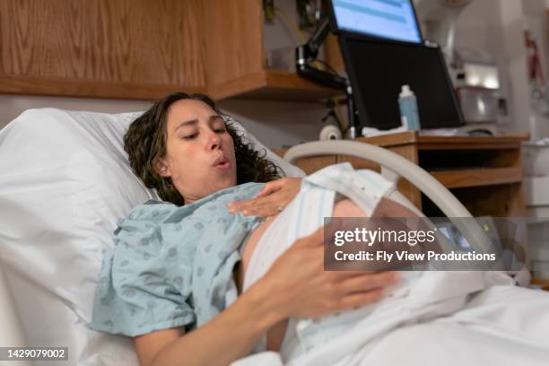 mujer embarazada que tiene contracciones y latidos cardíacos monitoreados en la cama del hospital - giving birth fotografías e imágenes de stock