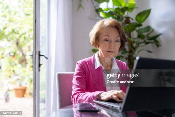 ältere frau zu hause, die an ihrem laptop arbeitet - testament schreiben stock-fotos und bilder