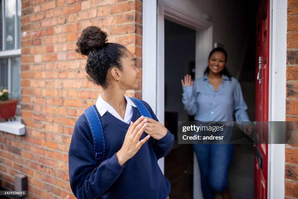 Girl going to school and waving goodbye to her mother