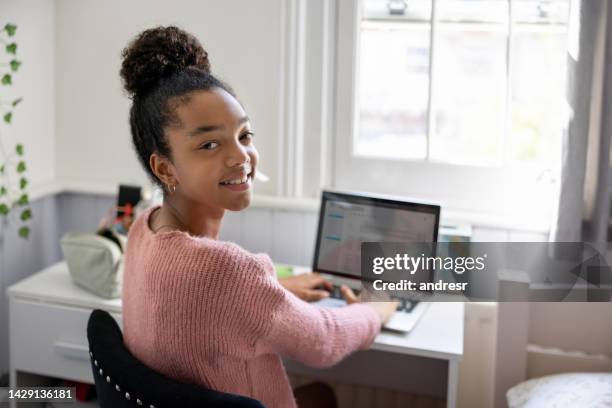 happy teenager girl at home working on her laptop in her bedroom - young girls homework stockfoto's en -beelden