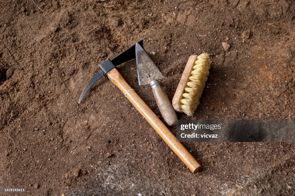 Pickaxe, trowel and brush. Tools in an archaeological excavation, digging concept