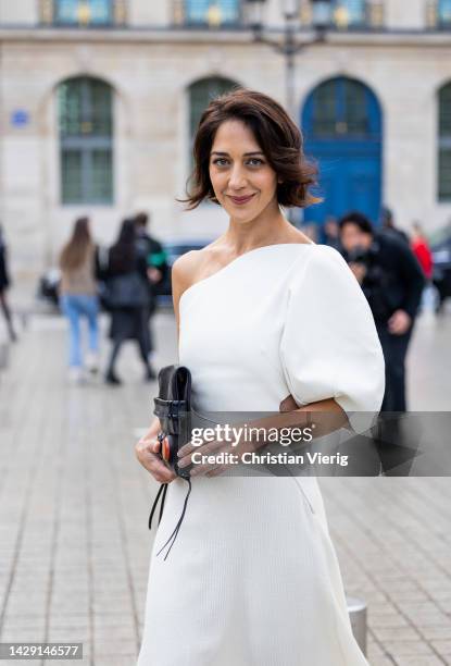 Zahra Amir Ebrahimi wears white asymmetric dress, black bag, boots outside Chloe during Paris Fashion Week - Womenswear Spring/Summer 2023 : Day Five...