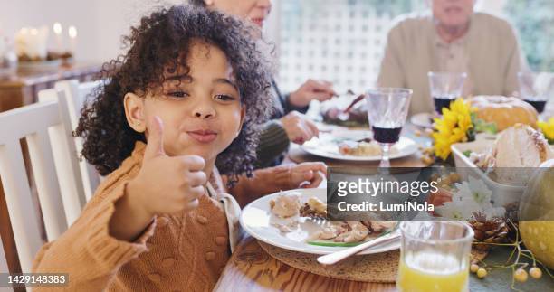 thumbs up, christmas and girl eating with family a delicious and tasty chicken or turkey meat for dinner at home, smile, happy and young child enjoys quality time, food and holiday with grandparents - smile woman child stockfoto's en -beelden