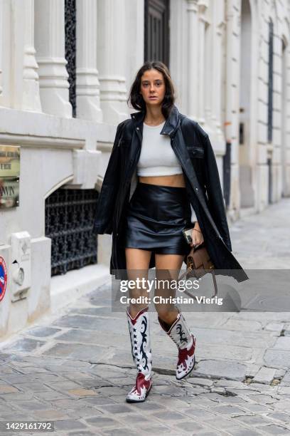 Guest wears black skirt, jacket, cowboy boots, brown Jacquemus bag during Paris Fashion Week - Womenswear Spring/Summer 2023 : Day Five on September...