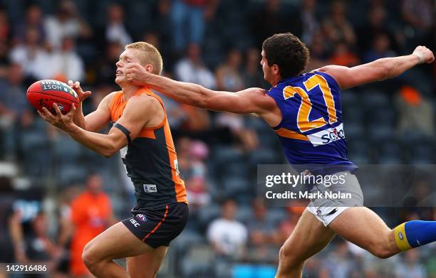 Adam Treloar of the Giants takes a mark and is hit high by Jack Darling of the Eagles during the round three AFL match between the Greater Western...