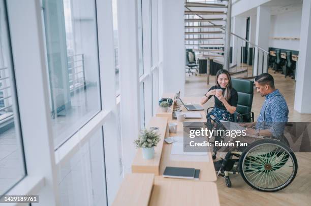 indian white collar male worker in wheelchair discussion with female asian chinese colleague coworking in creative office workstation beside window - bring your own device stock pictures, royalty-free photos & images