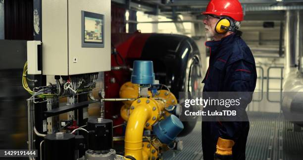 der erfahrenste heizwerksmitarbeiter untersucht die bedienung der maschinen im heizwerk. - district heating stock-fotos und bilder