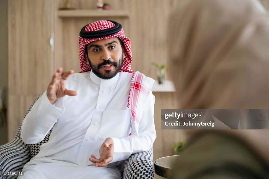 Saudi couple enjoying conversation while relaxing at home