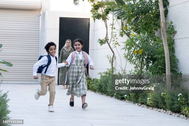 frères et sœurs saoudiens actifs se tenant la main et courant après l’école - arab student kids photos et images de collection