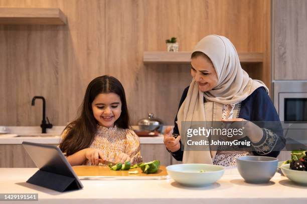 mature woman teaching granddaughter how to chop vegetables - groene paprika stockfoto's en -beelden