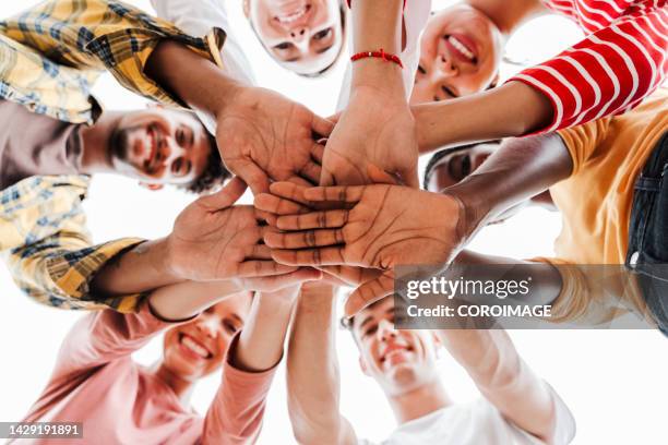 low angle close-up of college students putting hands toghether.  concept of friendship and teamwork - gelijkheid stockfoto's en -beelden