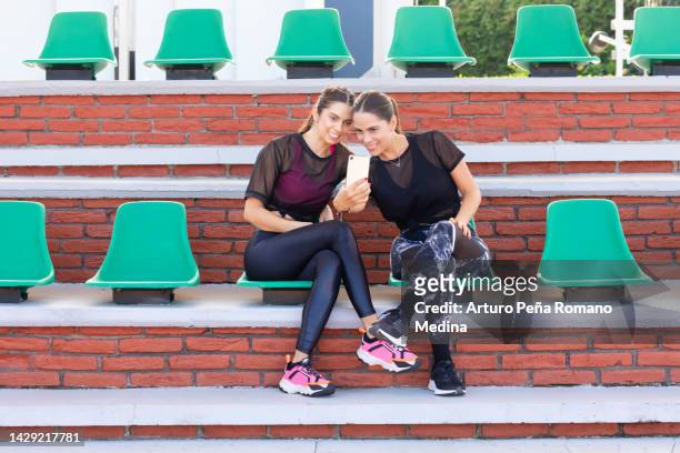 amigas latinas watching cell phones - amigas stock pictures, royalty-free photos & images