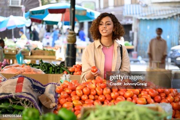 saudi woman selecting plum tomatoes at open air market - plum tomato stock pictures, royalty-free photos & images