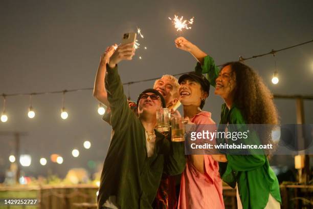 friends celebrating at party on rooftop. - rooftop party night stock pictures, royalty-free photos & images