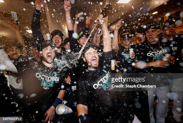Eugenio Suarez of the Seattle Mariners celebrates with teammates in the clubhouse after clinching a postseason birth after beating the Oakland...