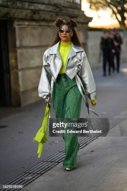 Guest wears silver sunglasses, silver earrings, a neon yellow lace print pattern turtleneck t-shirt, a silver shiny leather oversized / cropped...