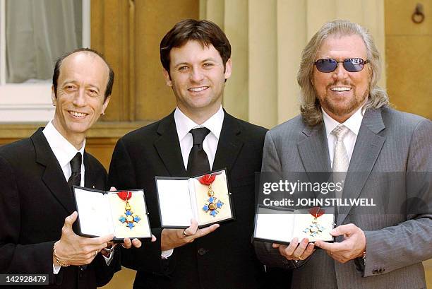 The two surviving members of the Bee Gees, Robin Gibb and Barry Gibb hold their CBE's along with Adam Gibb who received the honour on behalf of his...