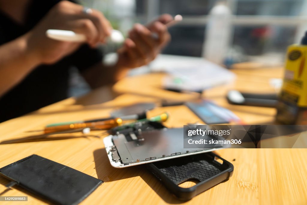 Close-up shot shows a mechanic using hand cleaning and replacing a smartphone device's screen new one
