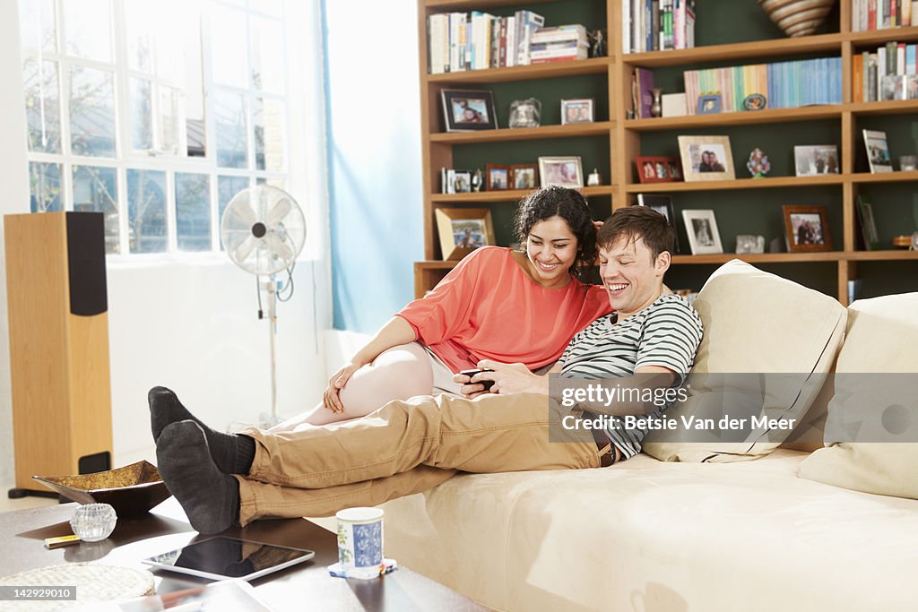 Couple looking at mobile phone in livingroom.