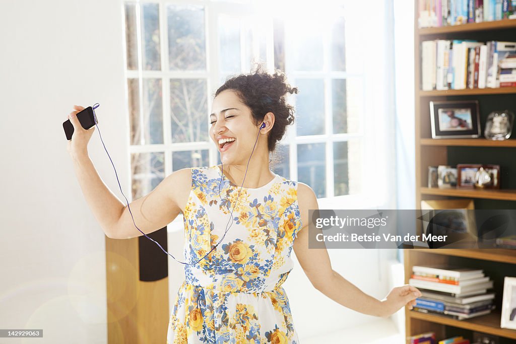 Woman dancing and singing in livingroom.