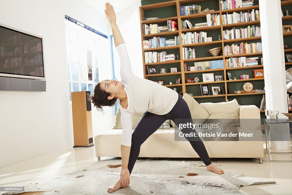 Woman doing yoga streches in livingroom.