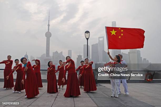 People pose for a group photo with Chinese national flag at the Bund to celebrate China's National Day on October 1, 2022 in Shanghai, China.