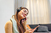 Relaxed adult young woman, wearing headphones, listening to music.