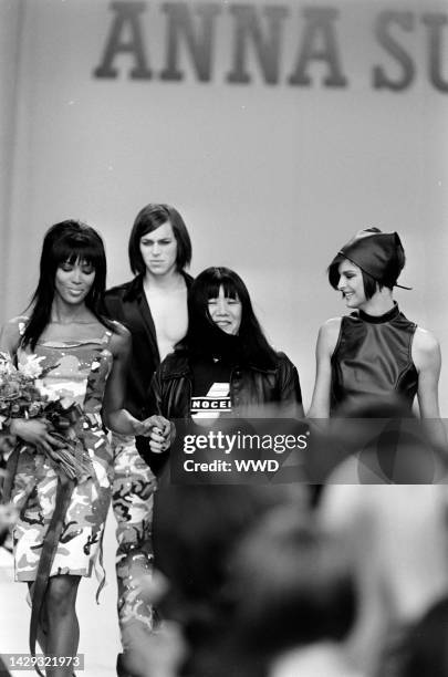 Designer Anna Sui takes a bow during the finale with models Naomi Campbell and Linda Evangelista