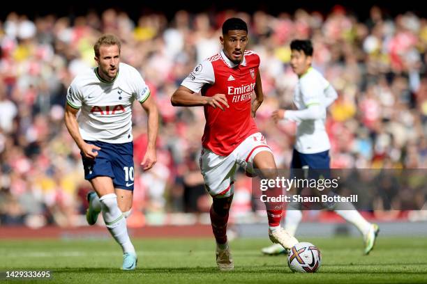 William Saliba of Arsenal runs with the ball whilst under pressure from Harry Kane of Tottenham Hotspur during the Premier League match between...