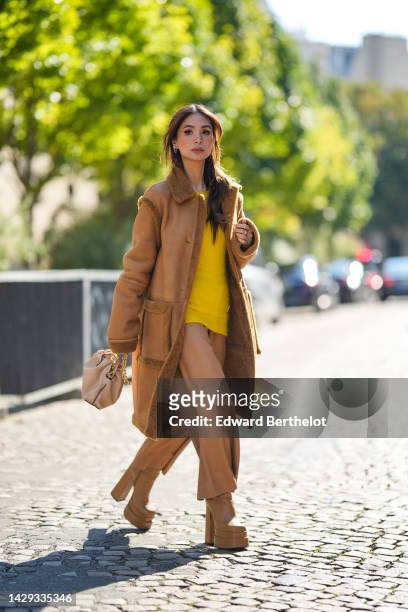 Heart Evangelista wears blue gray puffy sunglasses from Loewe, silver and pink rhinestones pendant earrings, a yellow wool oversized pullover from...
