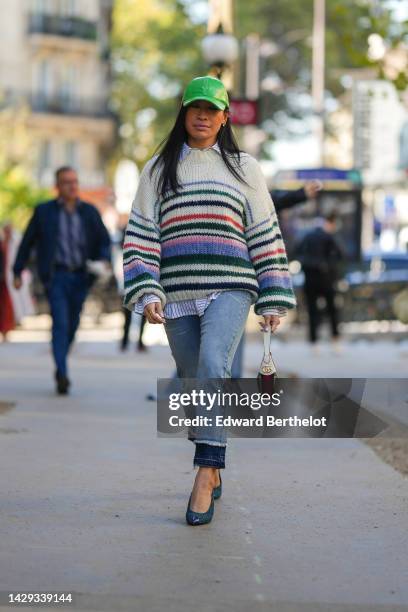 Miki Cheung wears a green shiny varnished leather cap, a white with small black striped print pattern shirt, a white latte with red / green / blue...