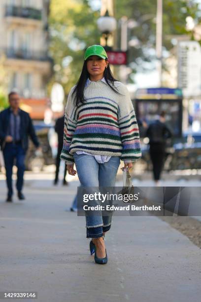 Miki Cheung wears a green shiny varnished leather cap, a white with small black striped print pattern shirt, a white latte with red / green / blue...