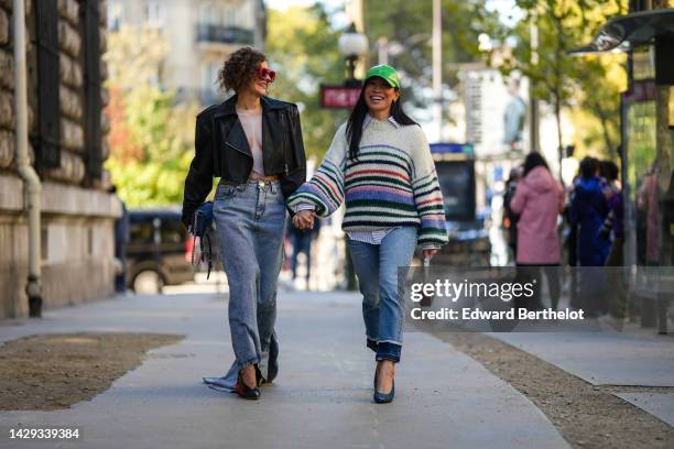 Renia Jaz wears red puffy sunglasses from Loewe, a black shiny leather cropped jacket, a white and beige body print pattern body top, a dark gray...