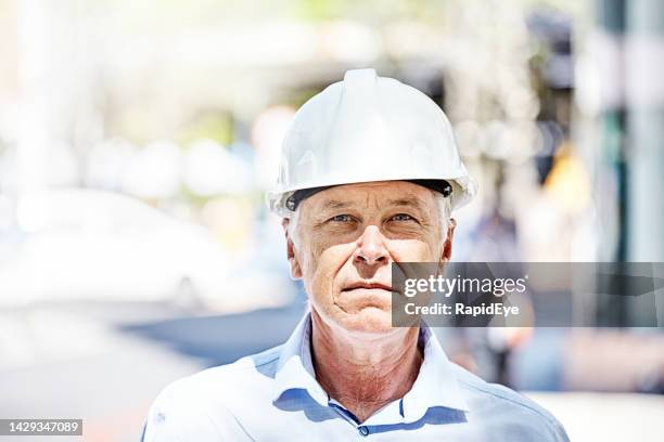 architect, civil engineer or construction boss looks at the camera while wearing a white hard hat - portrait man building stock pictures, royalty-free photos & images